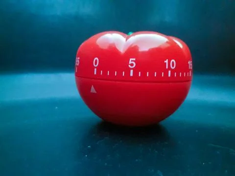 Red pomodoro timer in tomato shape on a black texture background. Foto stock