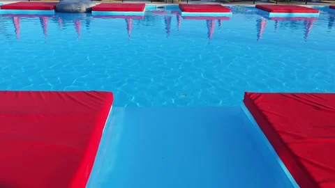 Red pool mattresses floating on a blue swimming pool Vidéo 312123010