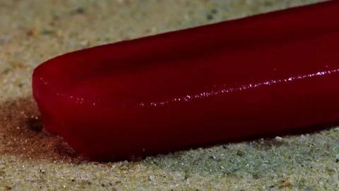 Red Popsicle Melts on Sand Stock Footage 75802376