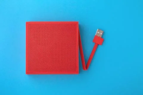 Red portable speaker with usb cable on blue background, flat lay Stock Photos