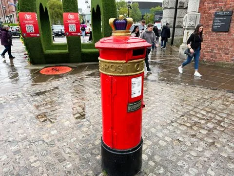 Red post box at Albert Dock in Liverpool, UK with crown top on wet cobblest.. Stock Photos