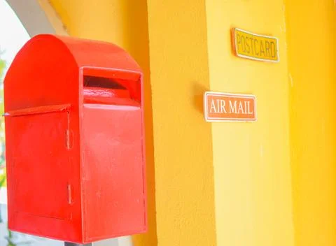 Red postbox in yellow background Stock Photos