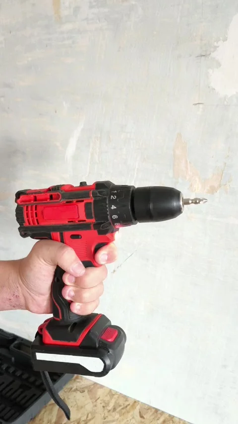 Red Power Drill turned on with drill bit in mans hand close-up. Man turns on Stock Footage 322894600
