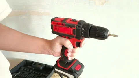 Red Power Drill turned on with drill bit in mans hand close-up. Man turns on Stock Footage 322894650