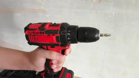 Red Power Drill turned on with drill bit in mans hand close-up. Man turns on Stock Footage 322894682