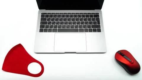 Red protective mask and computer mouse lie next to the laptop, close up view Fotos Stock