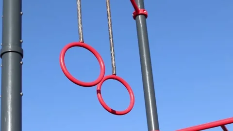 Red pull-up rings on the sky background Stock Footage 332169255