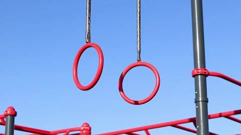 Red pull-up rings on the sky background Stock Footage 332169256