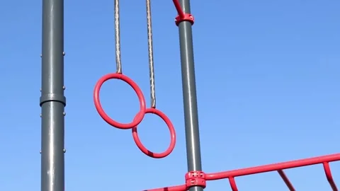 Red pull-up rings on the sky background Stock Footage 332169257