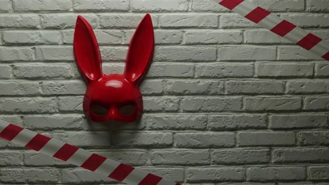 Red rabbit mask on a white brick texture wall and red and white signal tape Stock Footage 142795148