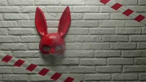 Red rabbit mask on a white brick texture wall and red and white signal tape Stock Footage 142795281