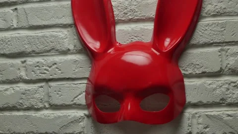 Red rabbit mask on a white brick texture wall and red and white signal tape Stock Footage 142795387