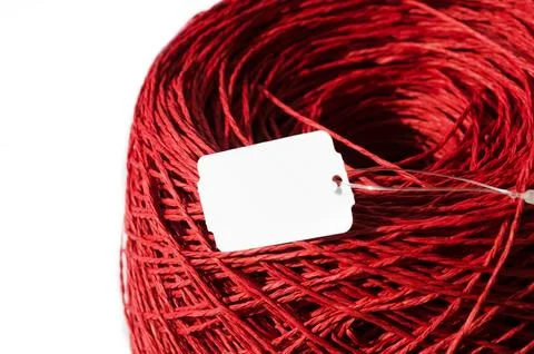 Red raffia on a white background. Close-up of a skein of raffia. Stock Photos