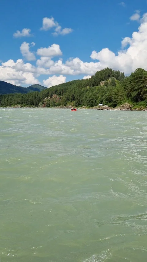 Red raft navigating a river flowing through a picturesque mountain valley under Stock Footage 316171810