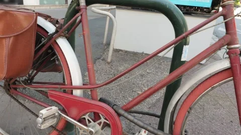 A red rare bicycle, securely attached to a green pole, attracts the attention of Vídeos de archivo 258827275