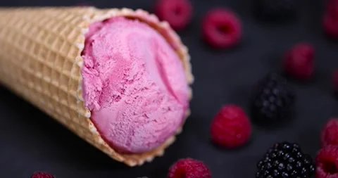Red raspberry ice cream in a waffle cone on a black background, delicious sweet Stock Footage 294696288