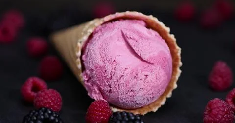 Red raspberry ice cream in a waffle cone on a black background Foto stock