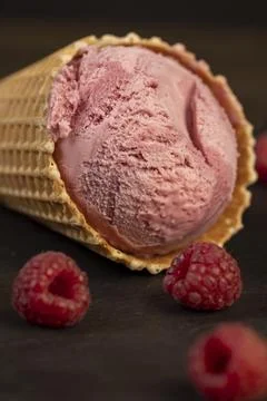 Red raspberry ice cream in a waffle cone on a black background Foto stock