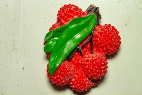 Red raspberry shaped soap with green leaf on white wooden surface Фото