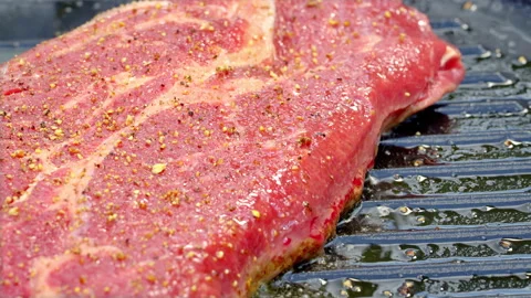 Red raw beef steak is being cooked in a hot cast iron pan with olive oil. Stock Footage 315904465