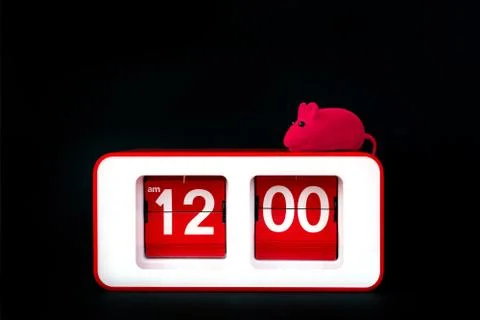 A red rectangular clock on a black background and a small toy rat 스톡 사진