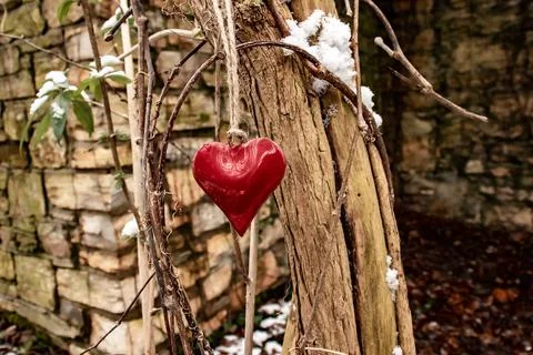 Red reflective heart in white snow hangs in a brown tree Stock Photos