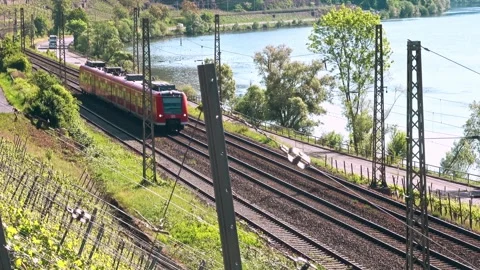 Red regional train moving along moselle river and vineyards Stock Footage 310041342