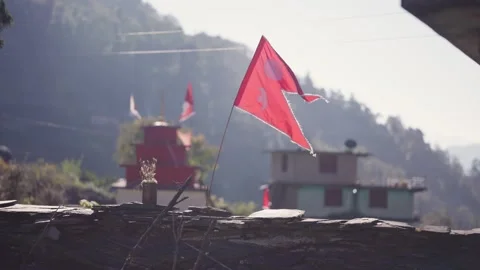 Red religious prayer flag fluttering above stone rooftop with traditional red Vídeos de archivo 343676199