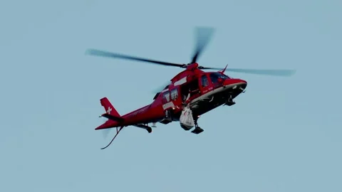 Red rescue helicopter flying in blue sky during emergency air ambulance mission 스톡 동영상 343820221