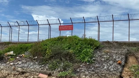 Red restricted area sign on high fence blue sky outdoor summer at Phuket Airport Stock Footage 278039659