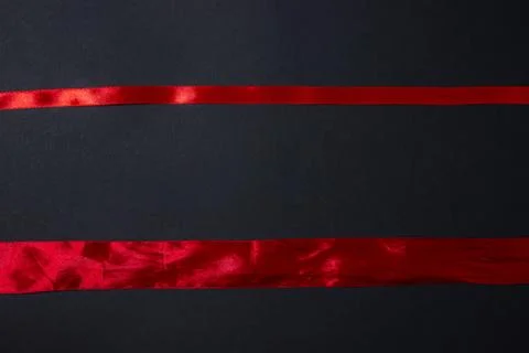 Red ribbon on a black background. Background for the inscription and logo. Stock Photos