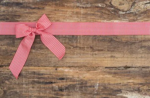 Red ribbon bow on rustic wooden background with copy space Stock Photos