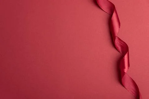 Red ribbon creating elegant border on crimson background Stock Photos