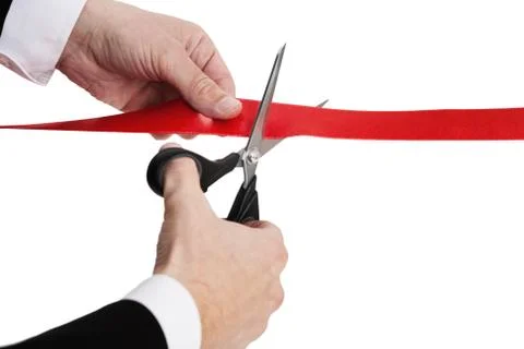 Red ribbon cutting with a pair of scissors Stock Photos