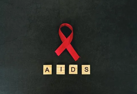 Red ribbon HIV, AIDS on gray background. Words AIDS. Stock Photos