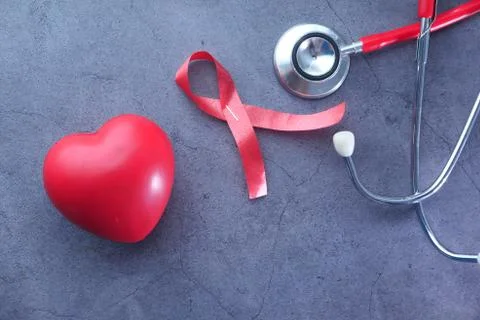 Red ribbon HIV, heart and stethoscope on black background. Stock Photos
