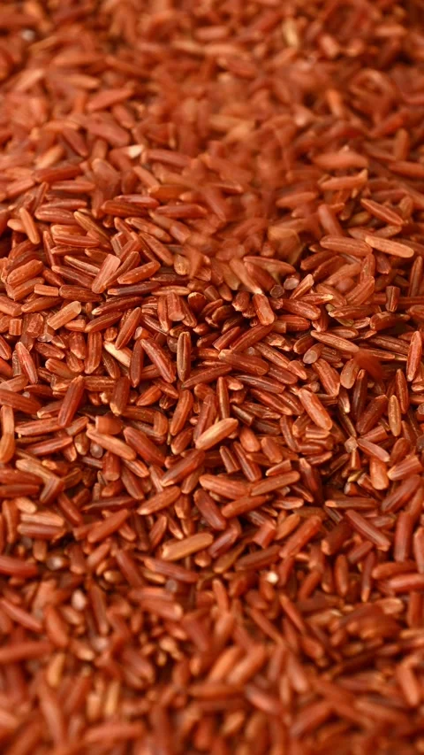 Red rice cascading and settling on wooden tabletop close up Stock Footage 331592527