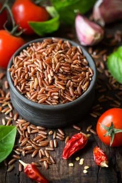 Red rice with condiments - cherry tomatoes, chili pepper, basil and garlic Stock Photos