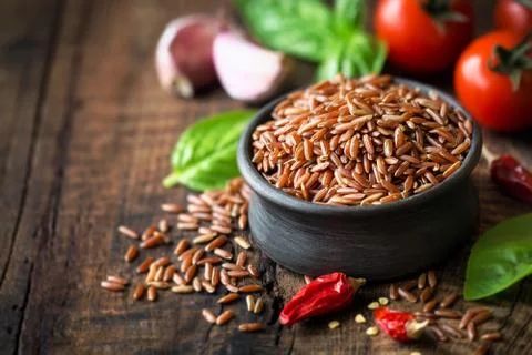 Red rice with condiments - cherry tomatoes, chili pepper, basil and garlic Stock Photos