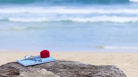 Red ring box and glasses on a notebook placed on a wooden beach plate 库存影片 77551360