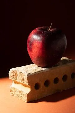 Red ripe apple on a brick. Creative photo in shadows. Stock Photos