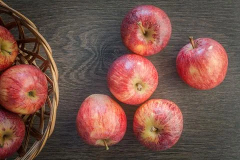 Red ripe Appples on a dark rustic wooden background, with a wooden basket. Stock Photos