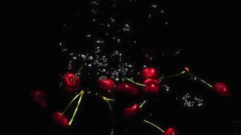 Red ripe cherries falling into water on black background. Stock Footage 201711596