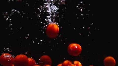Red ripe cherry tomatoes falling in transparent water on black background. Stock Footage 253364190
