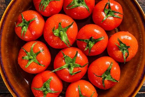 Red ripe tomatoes on rustic plate. Dark Wooden background. Top view Stock Photos
