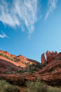 Red rock cliffs and spires tower among cirrus clouds and deep blue sky Stock-Fotos