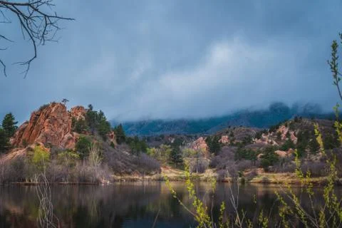 Red rock formations reflected in a lake as clouds pass by. Stock Photos