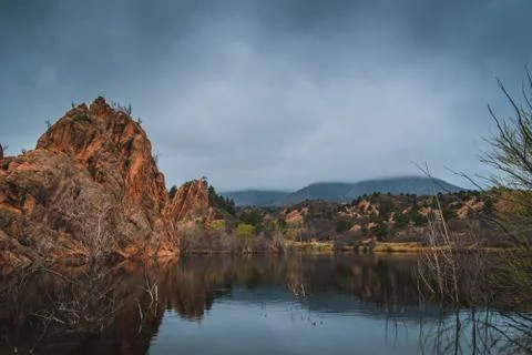 Red rock formations reflected in a lake as clouds pass by. Stock Photos