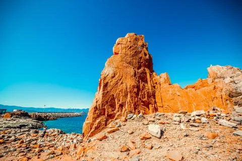Red rocks and blue sea in Rocce Rosse beach in Sardinia Stock Photos