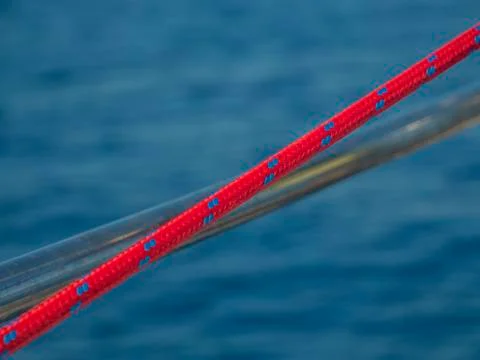 Red rope with blue dots in front of sailing boats fence. Stock Photos